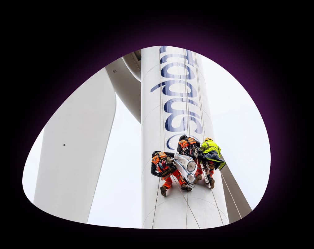 Three people climbing a wind turbine