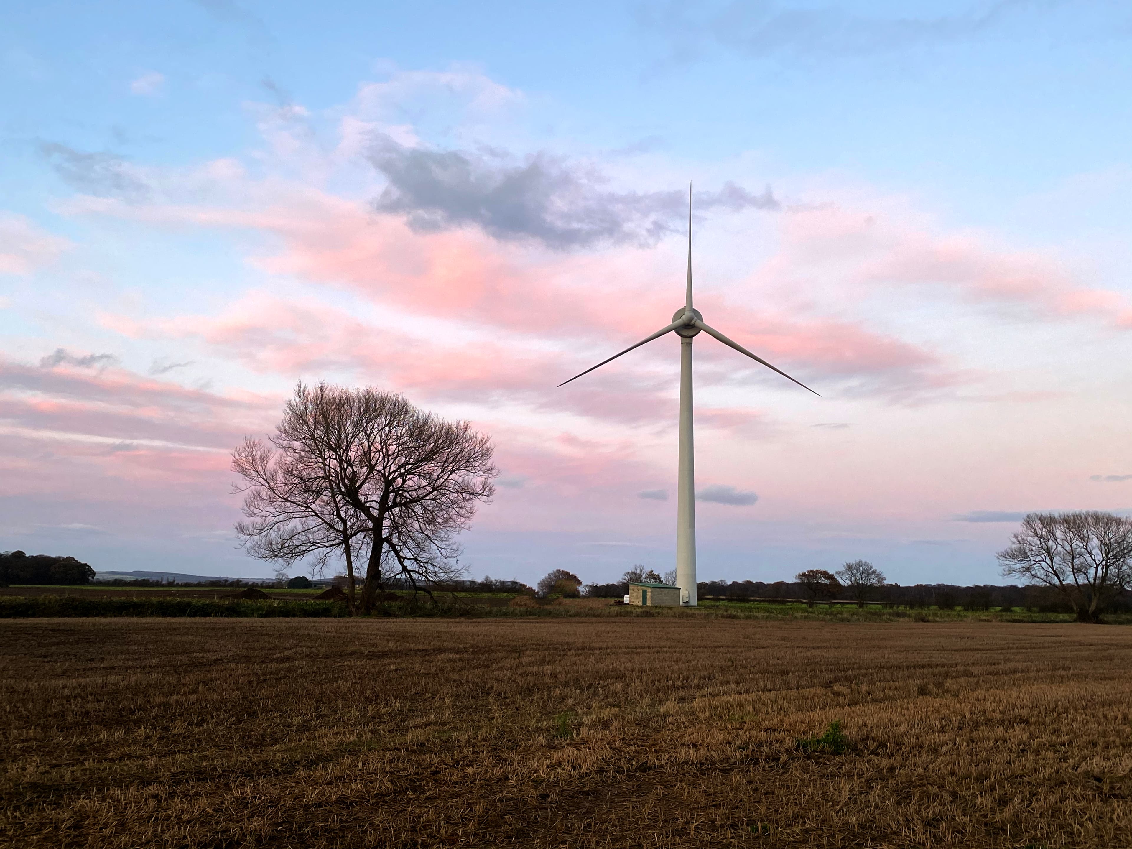 A wind turbine against a colourful sky backdrop