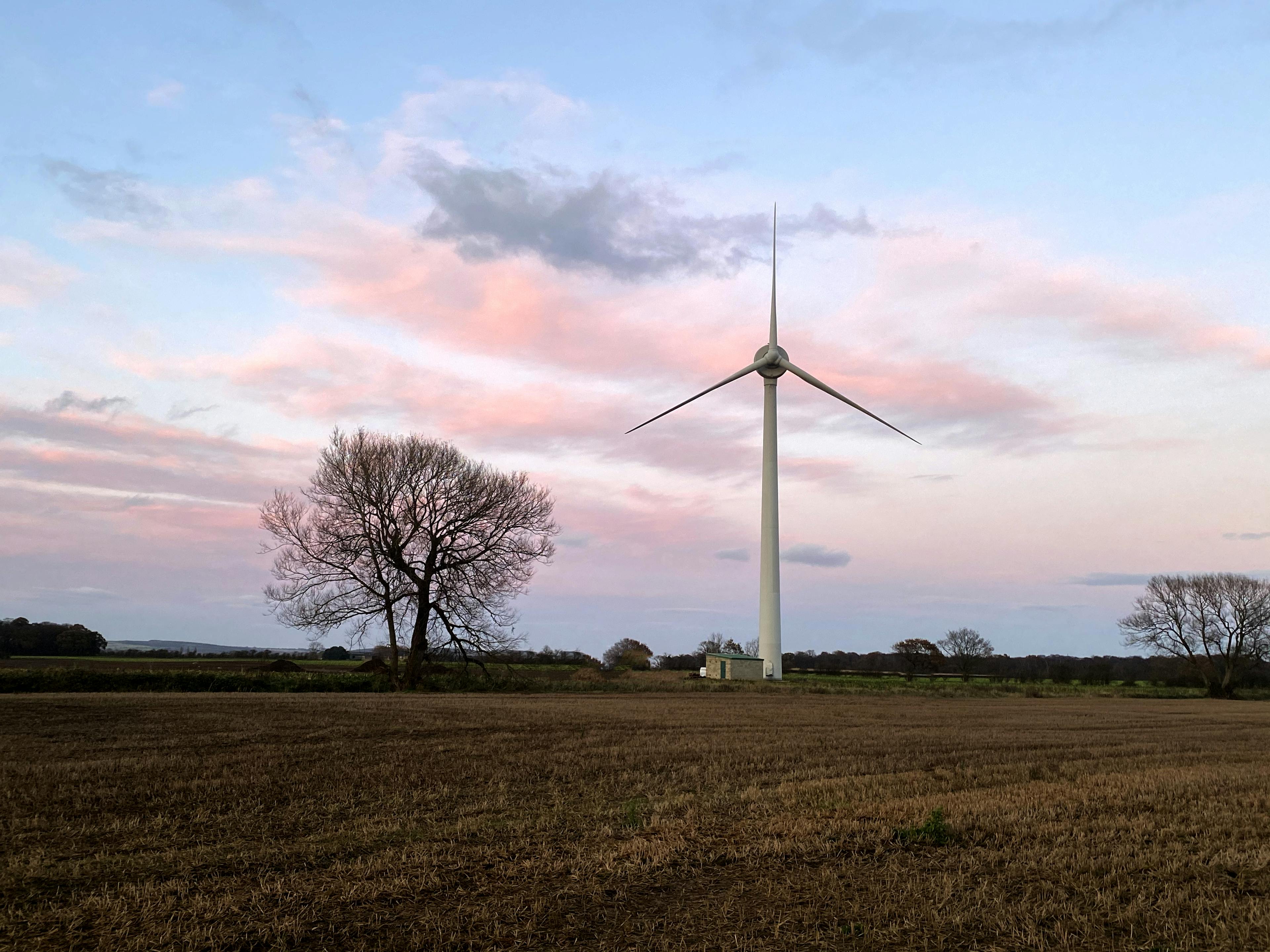 A wind turbine against a colourful sky backdrop